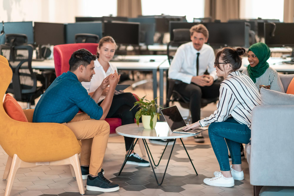 Multiethnic startup business team having brainstorming in relaxation area of modern office interior working on laptop and tablet computer. networking skills concept